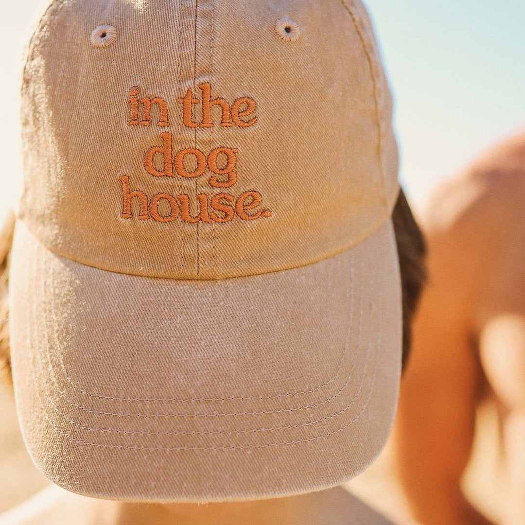 Dog House kids cotton cap in brown with orange embroidery, worn at the beach
