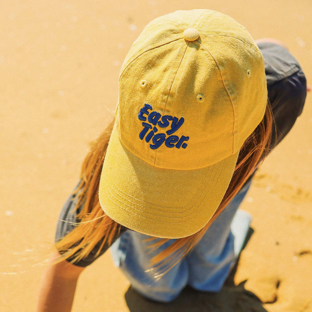 Girl at the beach in the Easy Tiger kids cotton cap in mustard yellow