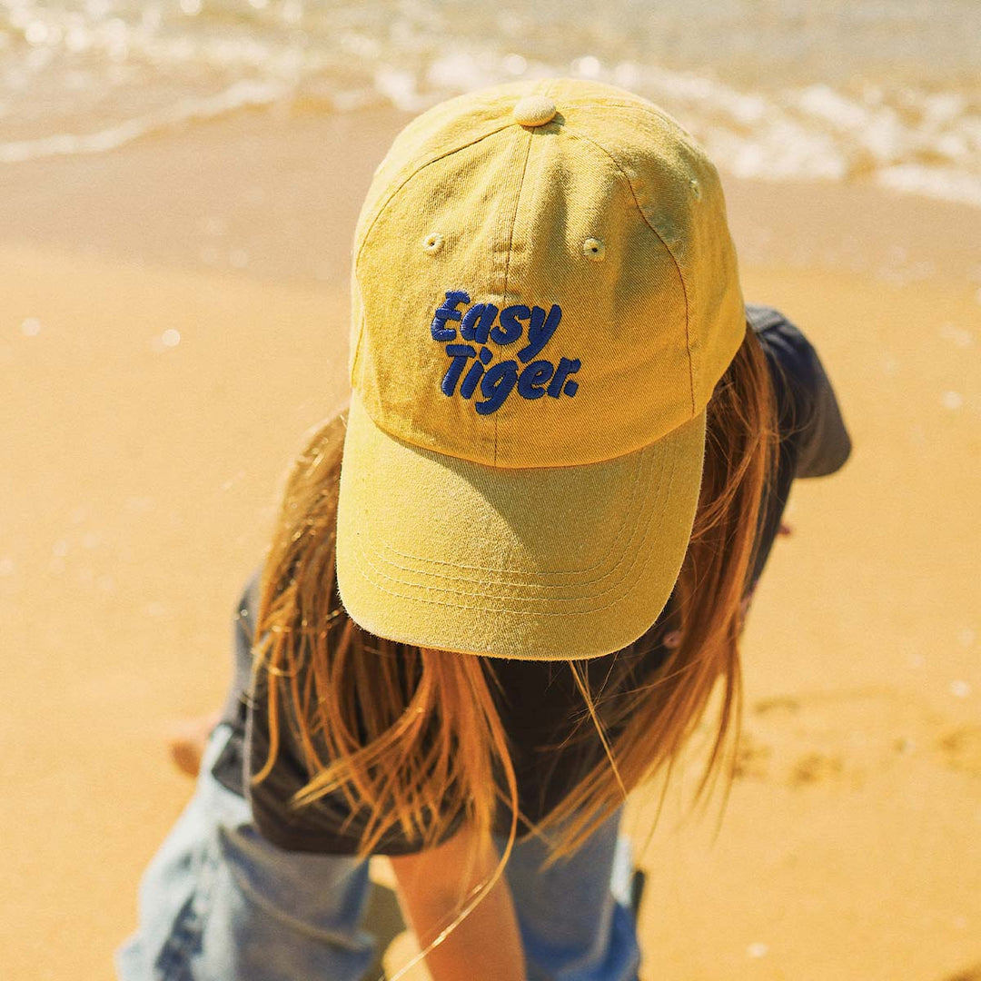 Kid wearing the mustard Easy Tiger kids cotton cap on the sand