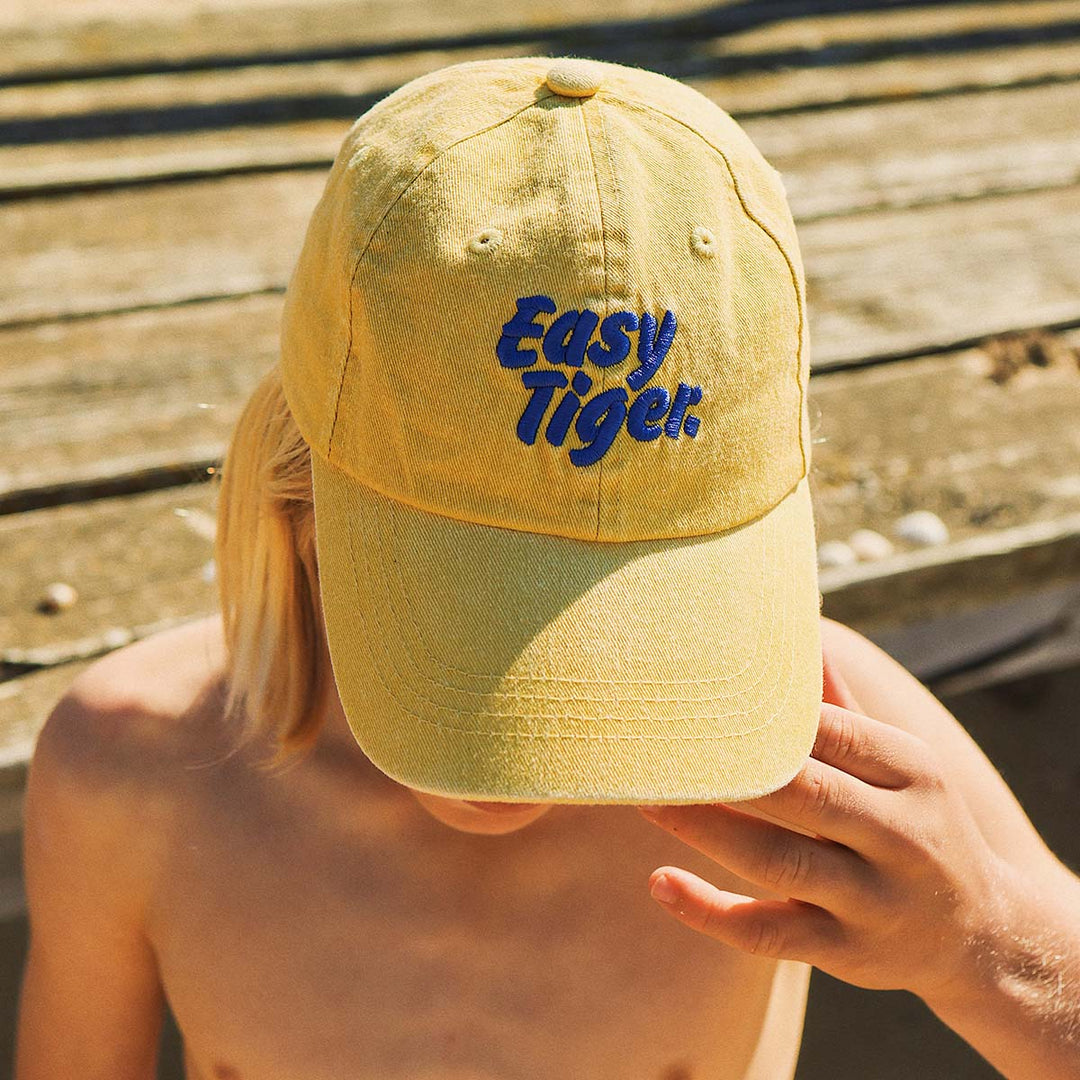 Close up of the Easy Tiger embroidery on the mustard kids cotton cap