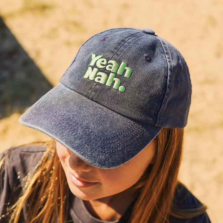 Girl wearing the navy Yeah Nah kids cotton cap