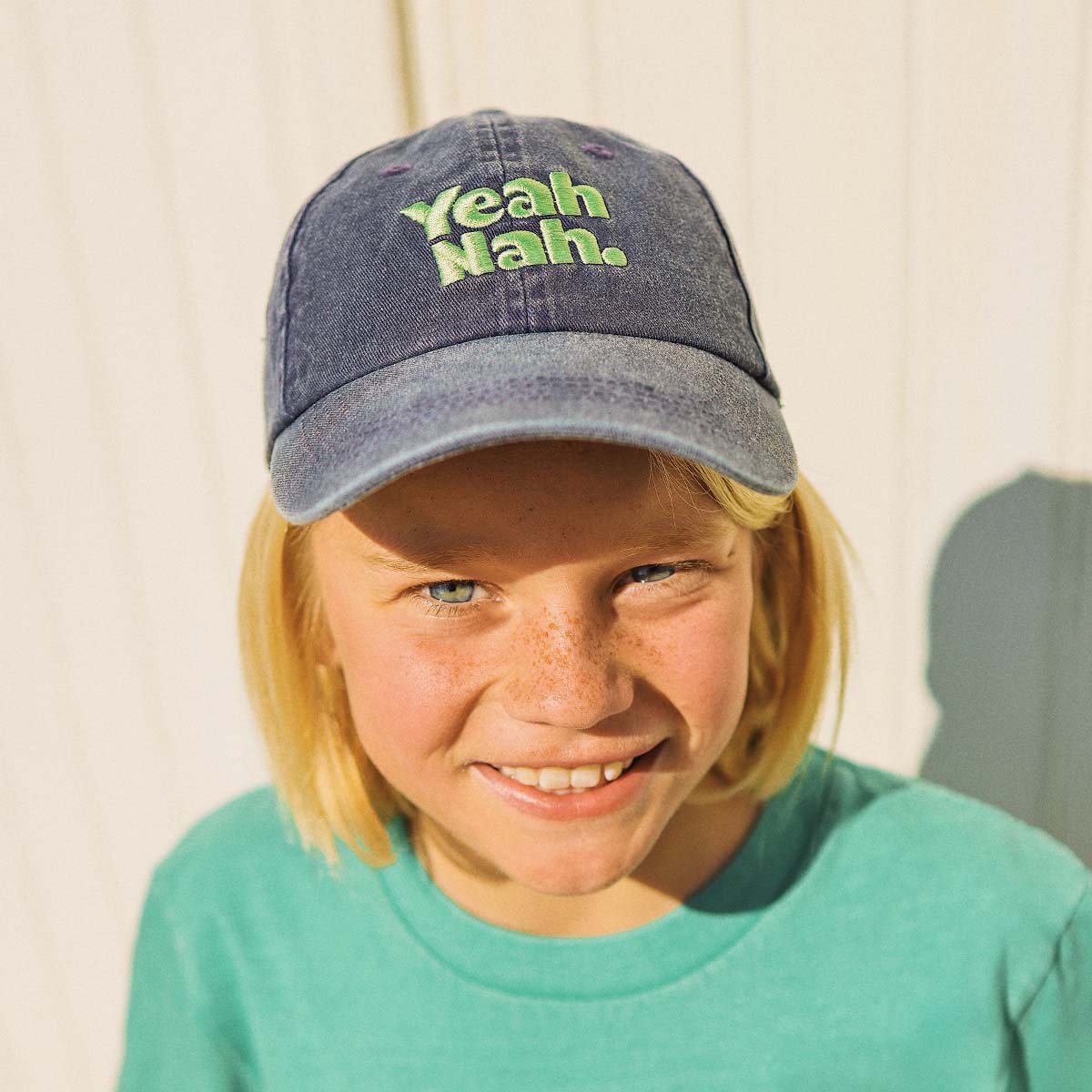 Boy wearing the Yeah Nah kids cotton cap in navy denim
