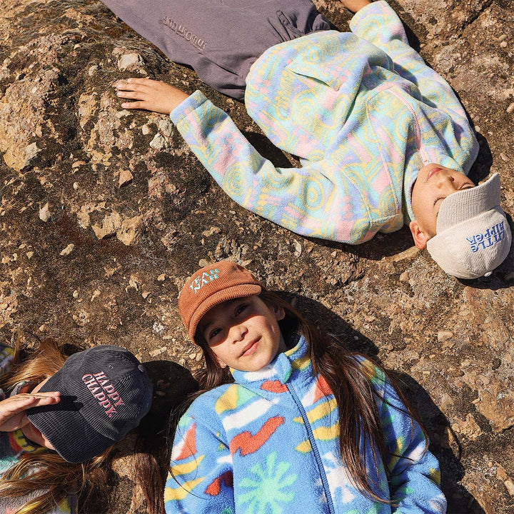 Kids lying on the rocks wearing Skwosh corduroy caps