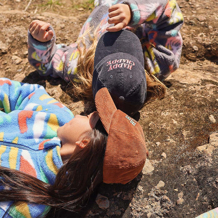 Kids wearing Skwosh corduroy caps lying on the rocks
