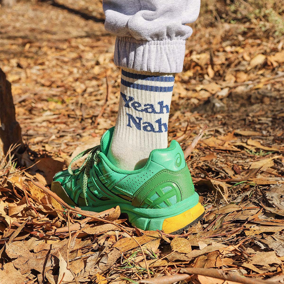 Child wearing the white Yeah Nah kids socks with green shoes