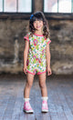 A little girl wearing a DOLLY ROMPER from Rock your Baby Online and pink sneakers.