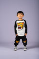 A young boy wearing a Rock your Baby Online TIGER RAGLAN T-SHIRT and black sweatpants.