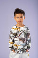 A young boy wearing a Primordial T-Shirt with dinosaurs on it from Rock your Baby Online.