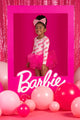 A girl in a pink dress is posing in front of a pink frame with balloons, wearing the Rock your Baby Online BARBIE SIGNATURE LEOTARD.