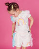 A little girl wearing a pink t-shirt and RAINBOW DREAMS RUFFLE SHORTS from Rock your Baby Online.