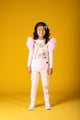 A little girl in a KITTY KAT T-SHIRT by Rock your Baby Online standing on a yellow background.