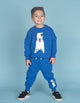 A young boy wearing a blue sweatshirt and PATCH TRACK PANTS with a dog on them by Rock Your Baby Online.