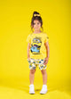 a young girl wearing Rock your Baby Online's MINIONS MAYHEM shorts and a yellow t-shirt.